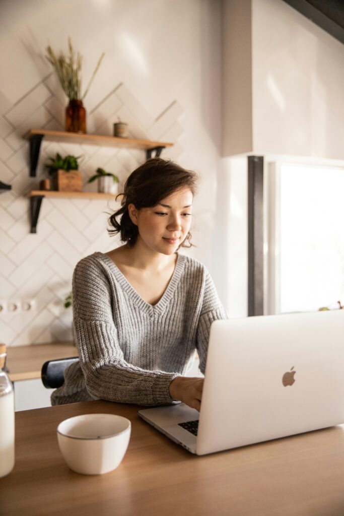 smiling-young-woman-using-laptop-in-kitchen